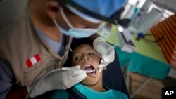 Un dentista revisa los dientes a un muchacho peruano en Surcubamba.