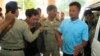 Chay Sarith (2-L) and Mao Hoeun (2-R) in light blue shirt, suspected attackers accused of beating two opposition lawmakers, are escorted by police officers at Phnom Penh Municipal Court in Phnom Penh, Cambodia, Nov. 4, 2015.