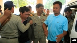 Chay Sarith (2-L) and Mao Hoeun (2-R) in light blue shirt, suspected attackers accused of beating two opposition lawmakers, are escorted by police officers at Phnom Penh Municipal Court in Phnom Penh, Cambodia, Nov. 4, 2015.