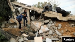 12일 팔레스타인 가자지구에 이스라엘의 공습이 있은 후 팔레스인 주민들이 잔해가 남은 건물을 살펴보고 있다. 