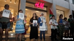 Demonstrators stand outside a store of Swedish fashion firm H&M during a protest against the Israeli offensive in Gaza, in Valencia, Spain, Aug. 7, 2014.