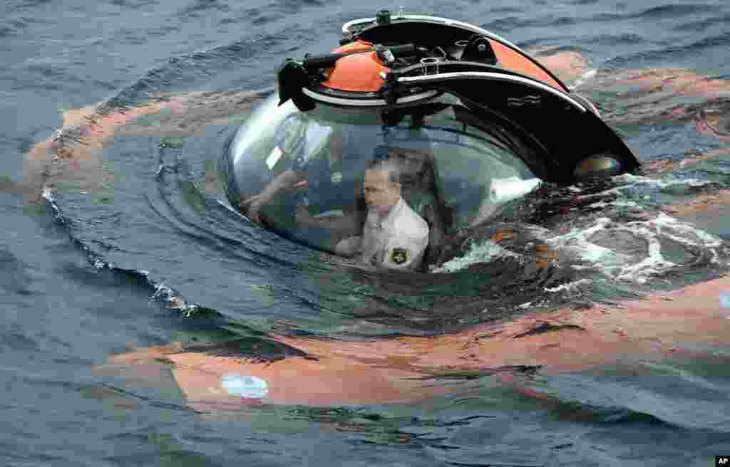Russian President Vladimir Putin, center, sits onboard a bathyscaphe as it plunges into the Black sea along the coast of Sevastopol, Crimea, to see the wreckage of a sunken ancient merchant ship which was found at the end of May. &nbsp;