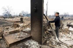 FILE - Anthony D-Amario, 18, looks through the remains of his home destroyed by the Marshall Fire in Louisville, Colorado, Dec. 31, 2021.