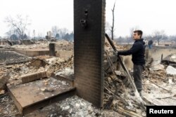 FILE - Anthony D-Amario, 18, looks through the remains of his home destroyed by the Marshall Fire in Louisville, Colorado, Dec. 31, 2021.