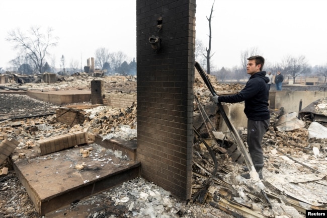 FILE - Anthony D-Amario, 18, looks through the remains of his home destroyed by the Marshall Fire in Louisville, Colorado, Dec. 31, 2021.