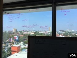 Babajob employees take notes on a window overlooking a neighborhood in downtown Bangalore. (E. Sarai/VOA)
