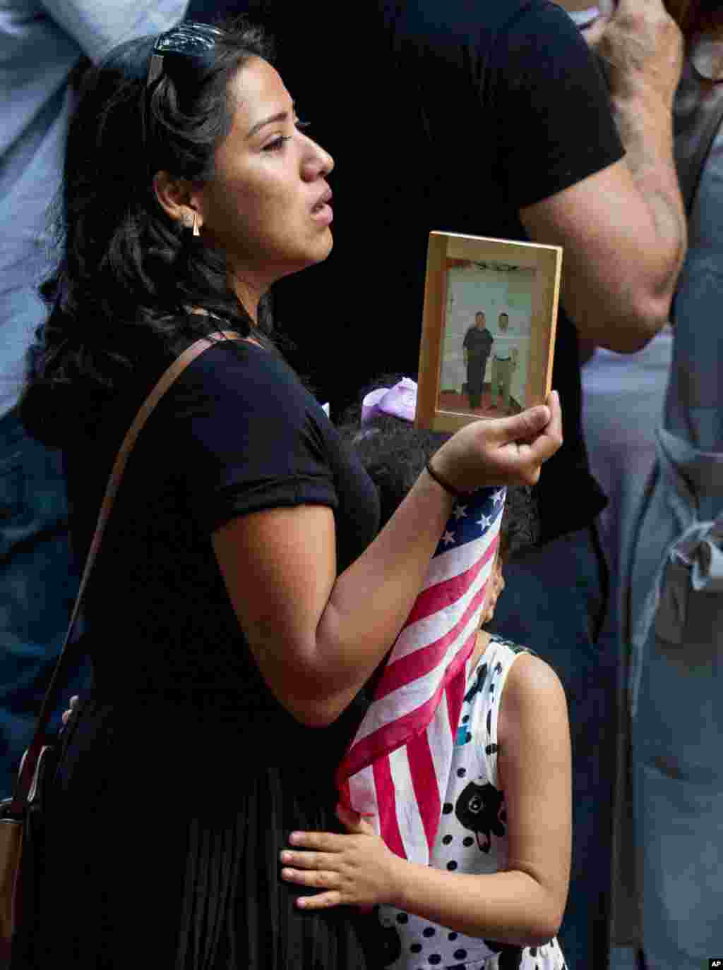 Seorang warga memegang foto orang yang dikasihi dalam acara peringatan serangan 11 September di World Trade Center di Memorial Nasional 11 September di New York (11/9). (AP/Andrew Harnik)