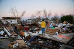 FILE - Nicolaus Kruse stands amongst the rubble of the home he grew up in after a devastating outbreak of tornadoes ripped through several U.S. states, in Mayfield, Kentucky, Dec.13, 2021.