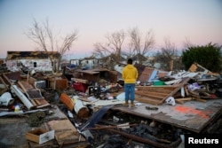 FILE - Nicolaus Kruse stands amongst the rubble of the home he grew up in after a devastating outbreak of tornadoes ripped through several U.S. states, in Mayfield, Kentucky, Dec.13, 2021.