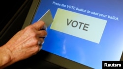 FILE - An elections official demonstrates a touch-screen voting machine at the Fairfax County Governmental Center in Fairfax, Virginia, Oct. 3, 2012.