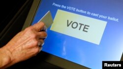 FILE - An elections official demonstrates a touch-screen voting machine at the Fairfax County Governmental Center in Fairfax, Virginia, Oct. 3, 2012.