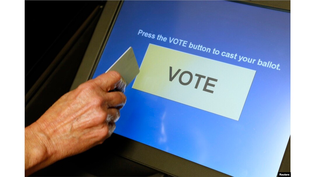 FILE - An elections official demonstrates a touch-screen voting machine at the Fairfax County Governmental Center in Fairfax, Virginia, Oct. 3, 2012.