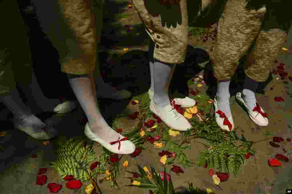 People walk past on the street covered with roses petals during the Corpus Christi procession, in Pamplona, northern Spain, June 18, 2014.