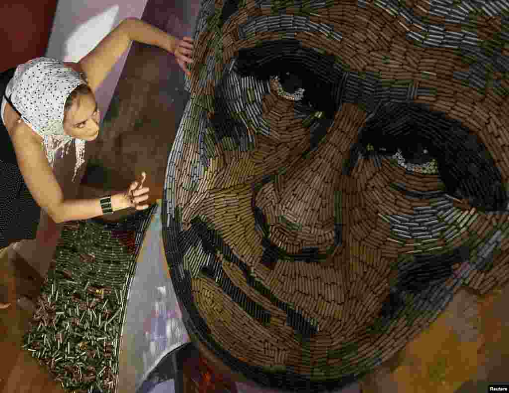 Ukrainian artist Dariya Marchenko works on a portrait of Russian President Vladimir Putin named &quot;The Face of War&quot; which is made out of 5,000 cartridges brought from the frontline in eastern Ukraine, in Kyiv.