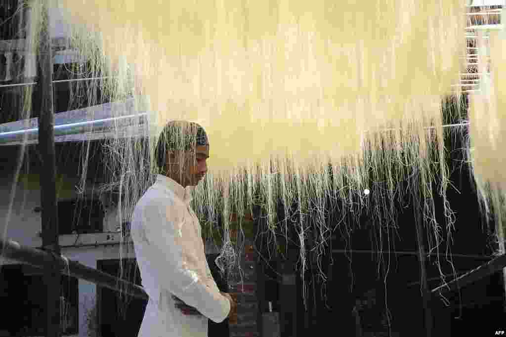 A Muslim worker offers Friday prayers as he stands under vermicelli noodles used to make traditional sweet foods popular in the fasting month of Ramadan, during a nationwide coronavirus lockdown, at a factory in Allahabad, India.