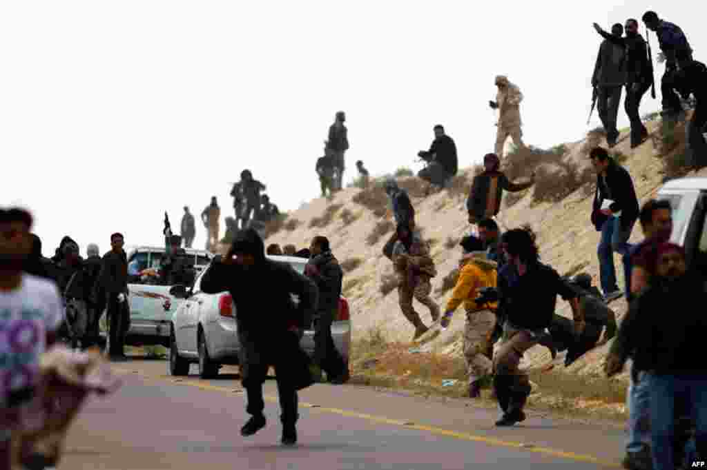 March 31: Rebels run for cover from artillery fired by forces loyal to Gaddafi, near Brega in eastern Libya. (Reuters/Finbarr O'Reilly)