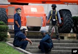 Workers wearing masks and bullet-proof vests take a break as they prepare to take down the statue of former Confederate general Robert E. Lee, which stands more than 100 feet tall, in Lee Circle in New Orleans, May 19, 2017.