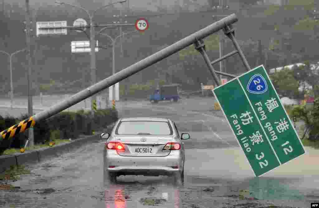 A car drives pass a collapsed traffic sign, toppled by strong winds of typhoon Meranti, as it slashes southern Taiwan.