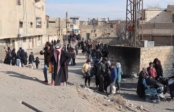 Syrians flee their homes in the Ghwayran neighborhood in the northern city of Hasakeh, Jan. 22, 2022, on the third day of fighting between the Islamic State (IS) group and Kurdish forces in Syria after IS attacked a prison housing jihadists in the area.