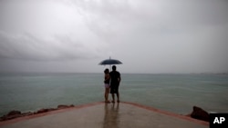 FILE - A couple looks out to sea as hurricane-related rainfall increases in Puerto Vallarta, Mexico. 
