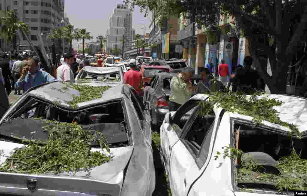 2013年4月30日，叙利亚首都大马士革的马尔贾广场发生爆炸后，人们走在街头。沿街可见一座建筑废墟和被炸毁的车辆。