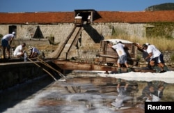 Workers push wagons full of salt at the Ston Saltworks site in Ston, Croatia, Aug. 8, 2017.