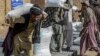 Afghan people carry sacks of food grains distributed as an aid by the World Food Program in Kandahar on Oct. 19, 2021. 