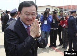 FILE - Former Thai prime minister Thaksin Shinawatra greets the media upon his arrival at the Siem Reap International Airport in Cambodia, April 14, 2012.