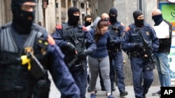 Catalan police officers detain a woman during an anti-drug trafficking operation in Barcelona downtown, Spain, Monday, Oct. 29, 2018.
