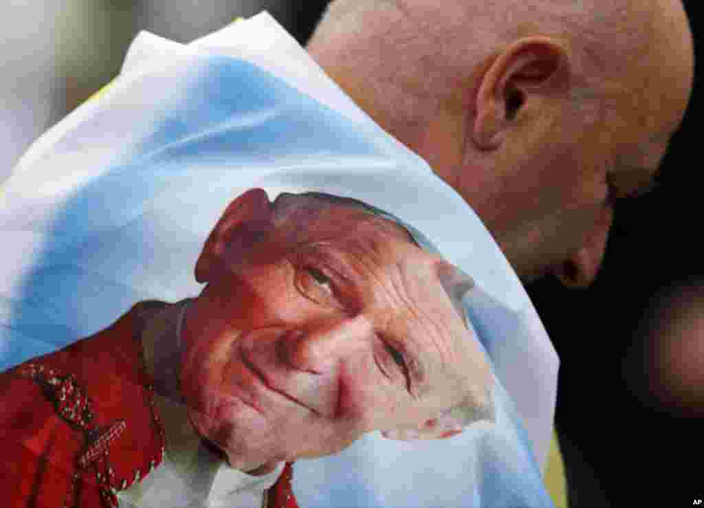 Un hombre se ha envuelto con una bandera que lleva el rostro de Juan Pablo II.