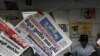 People stand in front of a newspaper stall, as headlines read, from left top, "Operation unsuccessful," "Might overrules right," and "Resolution against Sri Lanka passed," referring to the resolution passed by the U.N Human Rights Council in Geneva, in Co