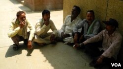 A group of workers relax and smoke during a midday break. (A. Pasricha/VOA)