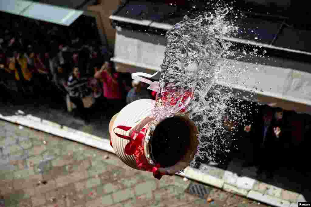 A clay pot full of water is thrown from a balcony during the Greek Orthodox Easter tradition of &quot;Botides&quot; on Holy Saturday marking the so-called &quot;First Resurrection&quot;, on the island of Corfu, Greece, April 30, 2016.