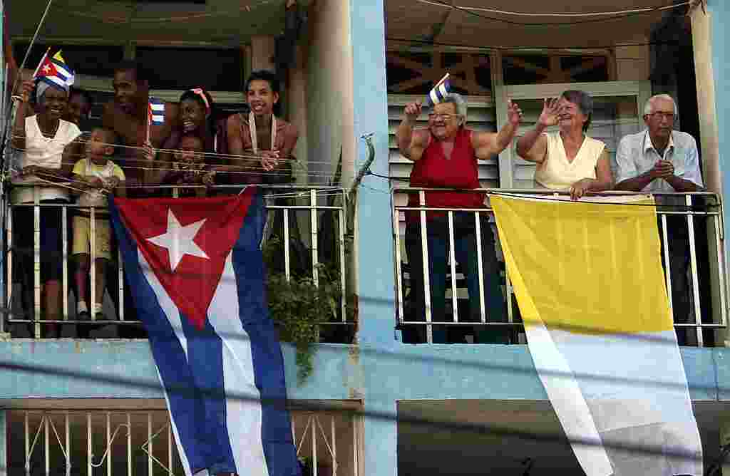 Residentes de Santiago de Cuba saludan el paso del papa Benedicto XVI con baderas cubanas y la bandera papal. (AP Photo/Ismael Francisco, Prensa Latina)