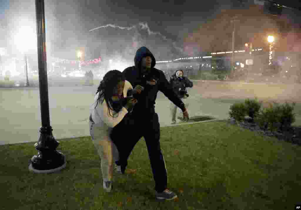 Manifestantes correm, fugindo do fumo do gás lacrimogénio lançado pela polícia para fazer face aos protestos depois de um Grande Júri ter decidido não acusar o agente da polícia Darren Wilson na morte de Michael Brown. Ferguson, Missouri. Nov 24, 2014