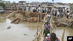 People queue to pass through a make-shift bridge after an heavy flood swept away a connecting bridge in Nigeria's south-west city of Ibadan, August 30, 2011.