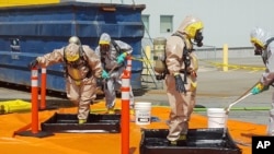 FILE - In this photo provided by the Royal Canadian Mounted Police, members of the RCMP go through a decontamination procedure in Vancouver after intercepting a package containing approximately 1 kilogram (2.2 pounds) of the powerful opioid carfentanil imported from China, June 27, 2016.