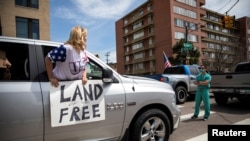 Trabajadores de la salud interrumpen los vehículos de manifestates que pedían el levantamiento de las restricciones por el coronavirus en Denver, Colorado, el 19 de abril de 2020.