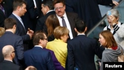 German Chancellor Angela Merkel (C) and fellow deputies leave after casting their vote on the approval to extend Greece's bailout, during a session of the Bundestag in Berlin, Feb. 27, 2015. 