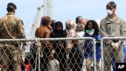 FILE - Migrants wait to disembark an Italian Navy ship in the port of Palermo, Sicily, southern Italy, May 2, 2014.