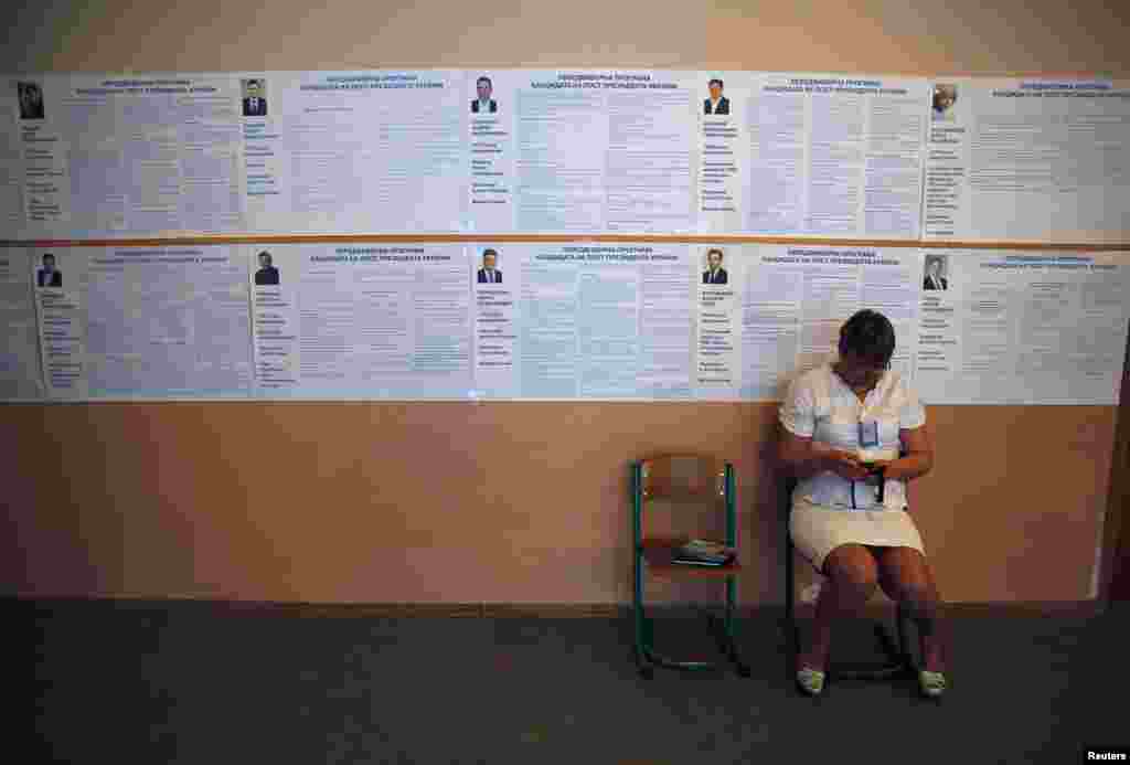 An election official sits in front of a wall covered with information of candidates during Ukraine's presidential elections at a polling station in the eastern Ukrainian town of Krasnoermeisk (Red Army), northwest of Donetsk, May 25, 2014. 