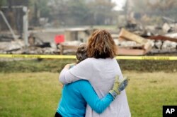 Carol Smith, left, gets a hug from her daughter Suzie Scatena, after seeing her fire-ravaged home for the first time, Aug. 2, 2018, in Redding, Calif.
