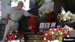 FILE - A man lays flowers during a commemoration ceremony at a monument for Kursk nuclear submarine crew in Moscow, Russia, Aug. 12, 2015. 