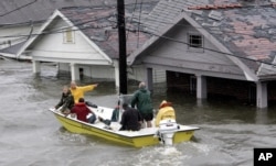 FILE - St. Berard Parish deputy sheriff Jerry Reyes uses his boat to rescue residents after Hurricane Katrina hit the area causing flooding in their New Orleans neighborhood, Aug. 29, 2005.