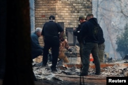 Yuba and Butte County Sheriff deputies retrieve remains of a deceased victim from a home during the Camp Fire in Paradise, California, U.S. November 10, 2018. REUTERS