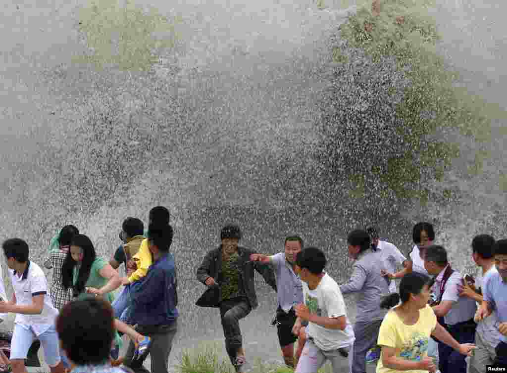 Warga lari menghindari ombak yang menabrak pembatas di sungai Qiantang, di Hangzhou, Zhejiang, China.