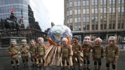 FILE - Oxfam campaigners dressed in the roles of 'ineffective fire-fighting world leaders' pose for a photo near the COP26 U.N. Climate Summit in Glasgow, Scotland, Nov. 12, 2021.