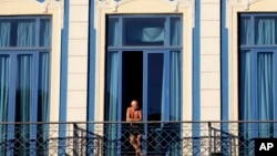 FILE - A tourist looks out from his hotel room's balcony in Havana, Cuba.
