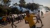 Pengungsi dan migran melarikan diri saat gas air mata ditembakkan oleh polisi anti huru hara selama bentrokan di dekat kota Mytilene di Pulau Lesbos, Yunani, pada 12 September 2020. (Foto: AFP)