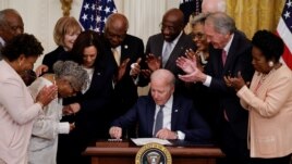 FILE - U.S. President Joe Biden is applauded as he reaches for a pen to sign the Juneteenth National Independence Day Act into law as Vice President Kamala Harris stands by in the East Room of the White House in Washington, U.S., June 17, 2021. (REUTERS/Carlos Baria)